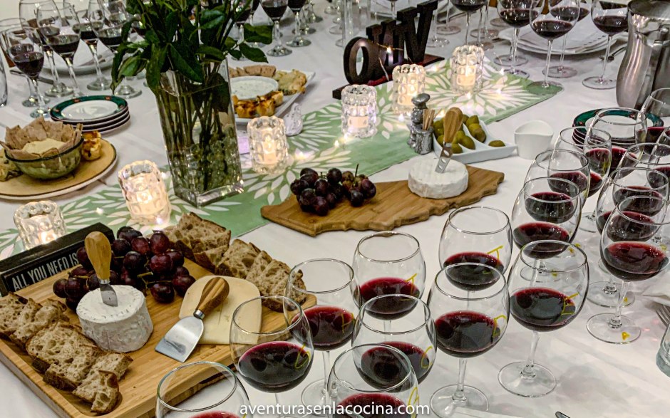 Mesa con varias copas de vino tinto, queso y pan. Una cata a ciegas de tintos.