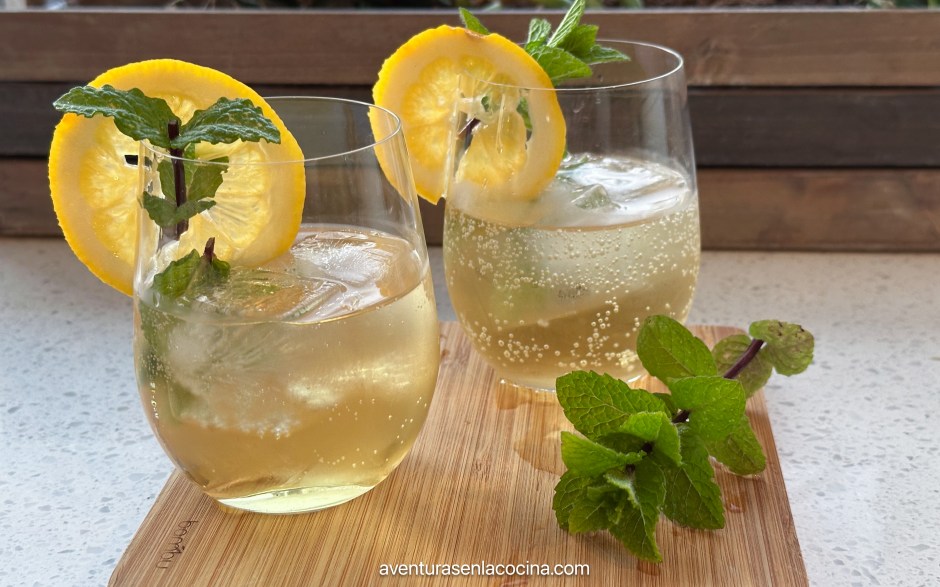 coctel Hugo Spritz servido en un vaso de vino sin tallo. Licor don rodaja de limon y ramita de menta. Aventuras en la cocina