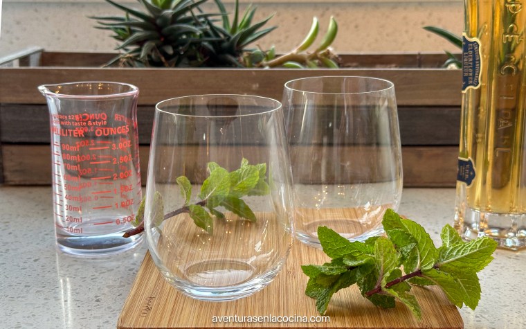 coctel Hugo Spritz servido en un vaso de vino sin tallo. Licor don rodaja de limon y ramita de menta.